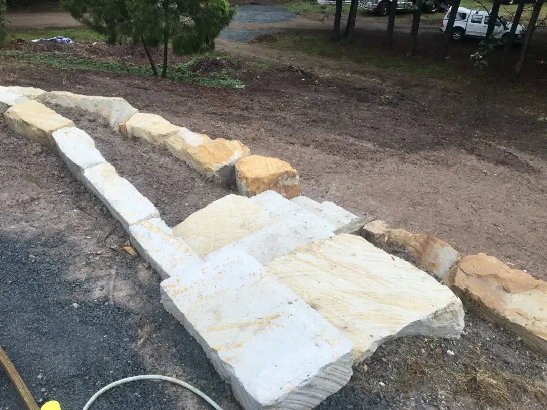 Sandstone slab entrance steps being laid at the driveway edge