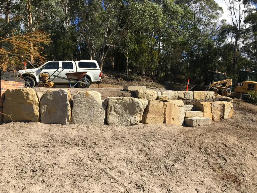 Sandstone boulder retaining wall with integrated steps up to the new parking area