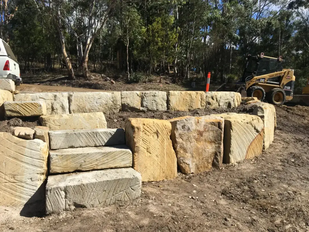 Sandstone boulder wall and steps nearing completion, with site machinery still on site