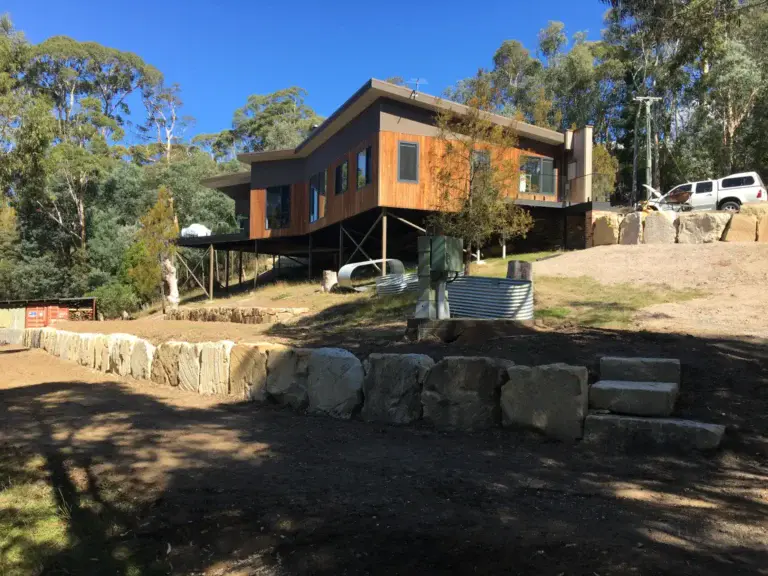 Modern home on stilts on a steep block in Kingston, with a new sandstone boulder retaining wall
