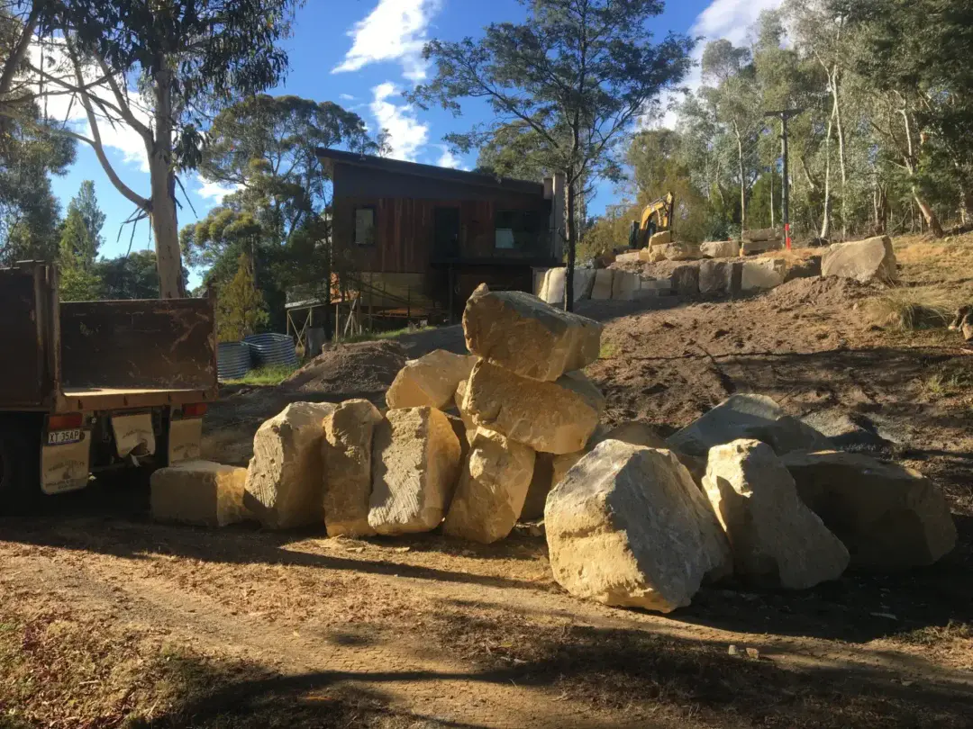 Truckload of sandstone boulders delivered and unloaded on site ahead of wall construction