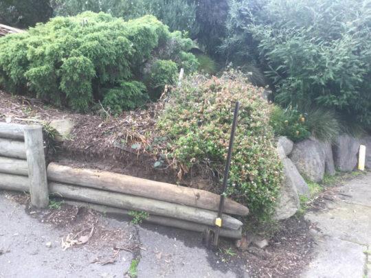 Collapsed timber log retaining wall before replacement