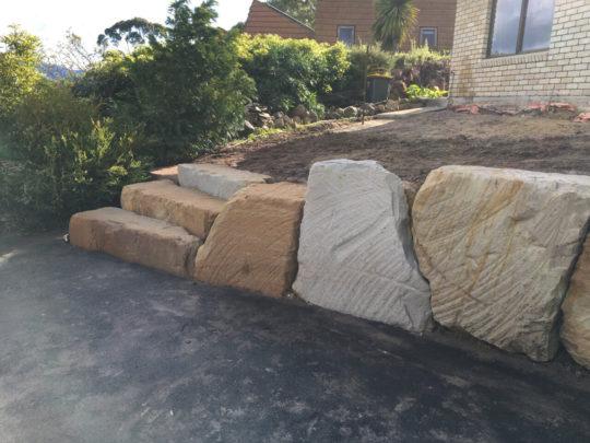 New sandstone boulder retaining wall and steps built beside the driveway